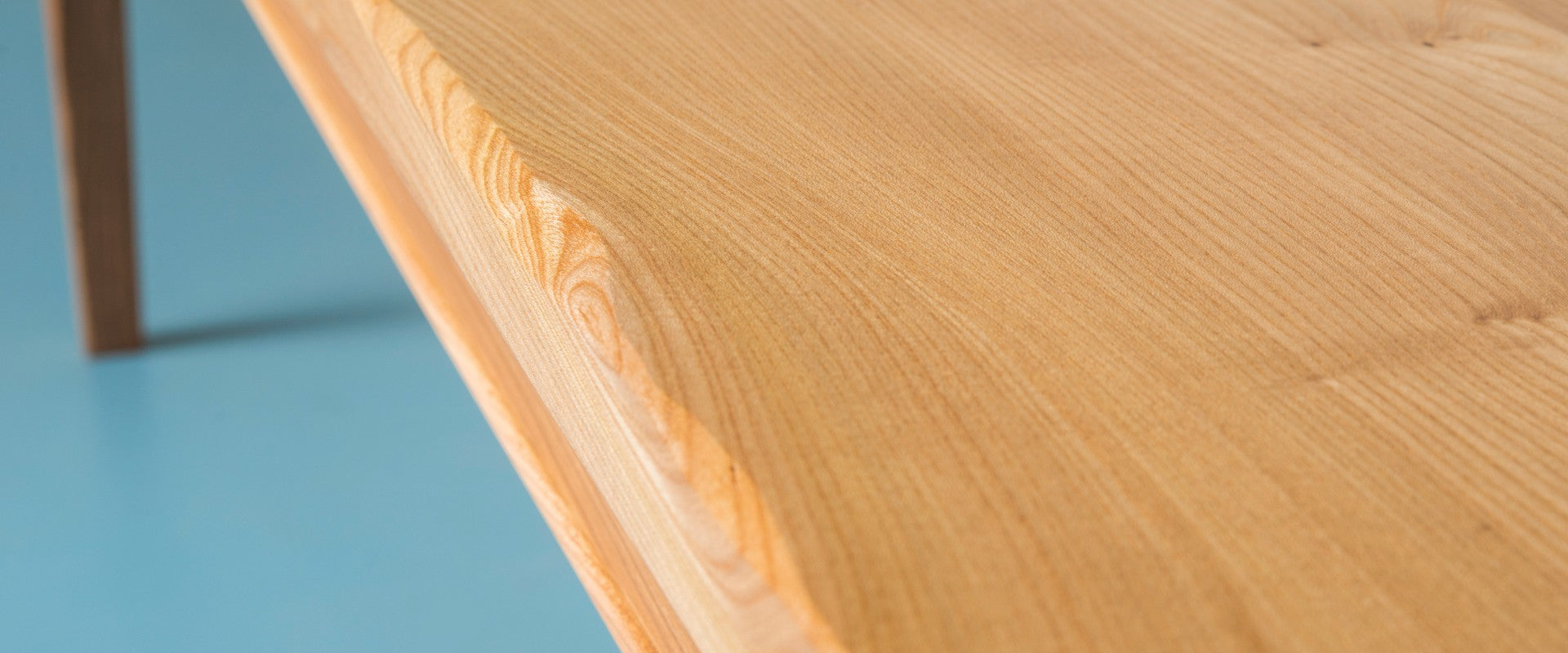 The side view of an elm table stood on a blue floor.