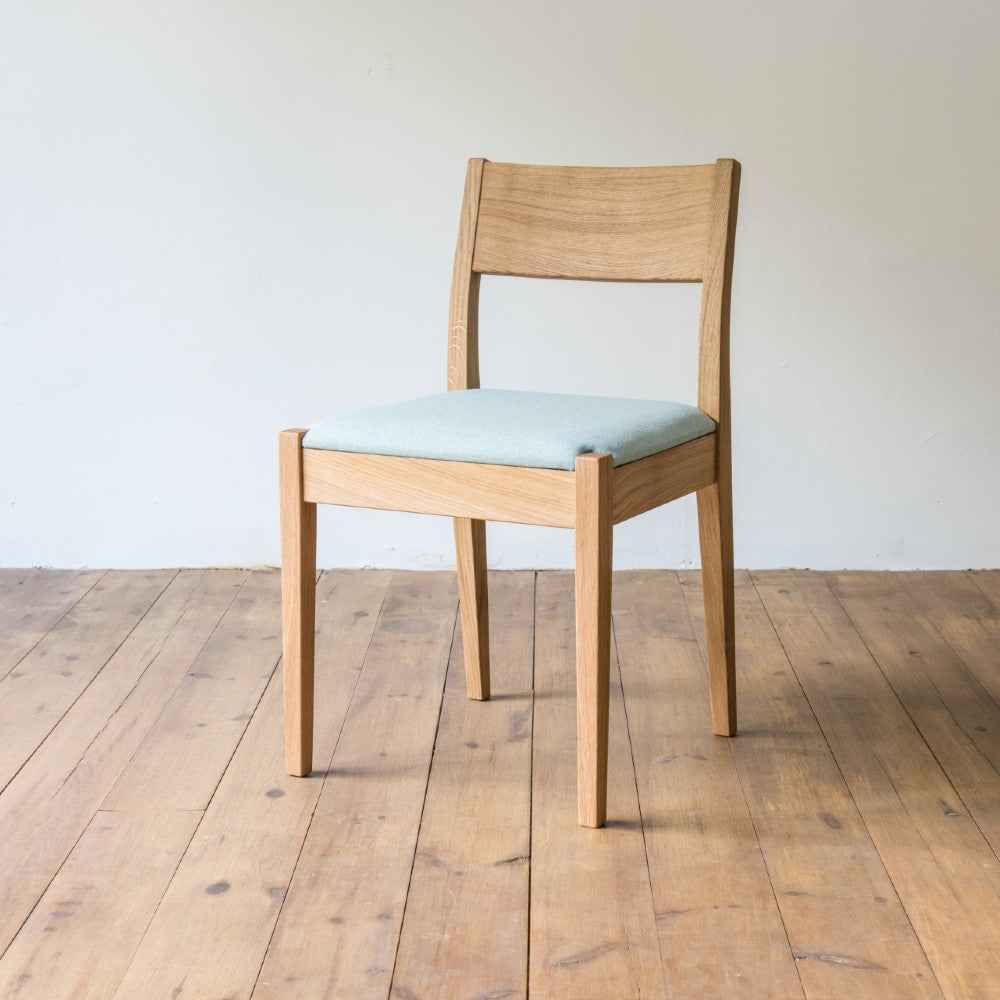 front left and side view of orpago hand made bespoke brampton kitchen dining lowback chair made from oak and a clear oiled finish with an upholstered seat and seat cushion
